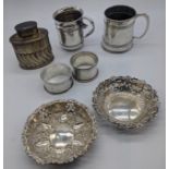 A collection of silver items to include 2 mugs, a tea caddy, 2 napkin rings, 2 bonbon dishes,