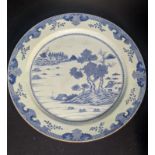 A large Chinese 18th century blue and white charger depicting a landscape scape and floral decor,