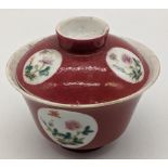 A Chinese Guangxu period (1875-1908) red glazed bowl with lid, depicting scenes of flora and