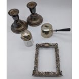 A collection of silver items to include a picture frame, brandy warmer pan, dwarf candlesticks and a
