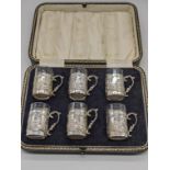 A set of 6 early 20th century silver shot cups with glass liners, repousse embossed with figural
