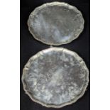 A pair of George III silver salvers, pie crust edge, raised on three scrolling feet, crested,