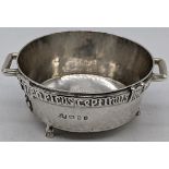 A small silver Arts and Crafts twin handled bowl raised on three feet with Celtic style banding,