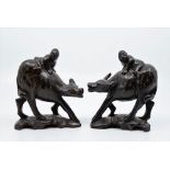 A pair of Chinese hardwood men riding water buffalo having decorative silver inlay.