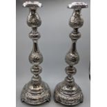 A pair of early 20th century Shabbat candlesticks, embossed decor, raised on three feet, filled