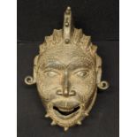 A Nigerian brass or bronze helmet mask, raised coiffure, probably Benin