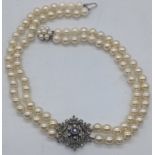 A diamond and sapphire simulated pearl choker, the clasp with a central round cut sapphire flanked