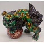 A Japanese sancai glazed pottery dragon on ball, H.18cm L.20cm