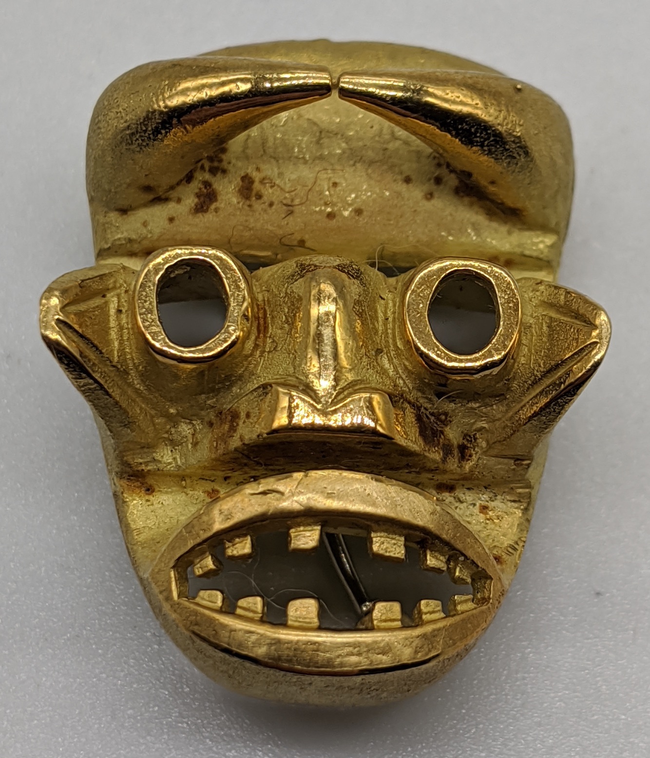 An 18ct gold African mask pendant/brooch, marks for 18ct and tested as 18ct, 20g, L.3.5cm