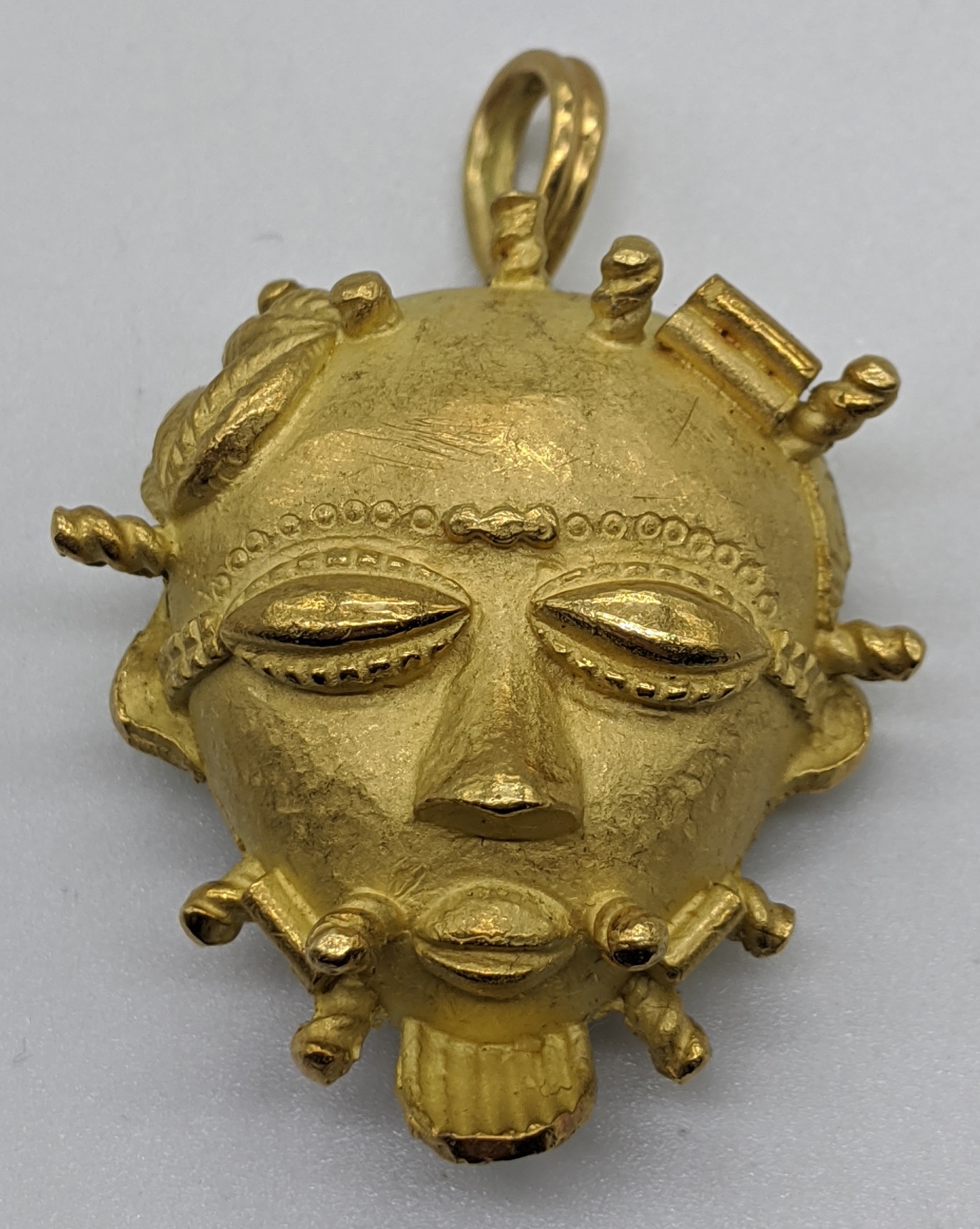 An 18ct gold African mask pendant/brooch, marks for 18ct and tested as 18ct, 35g, L.4cm