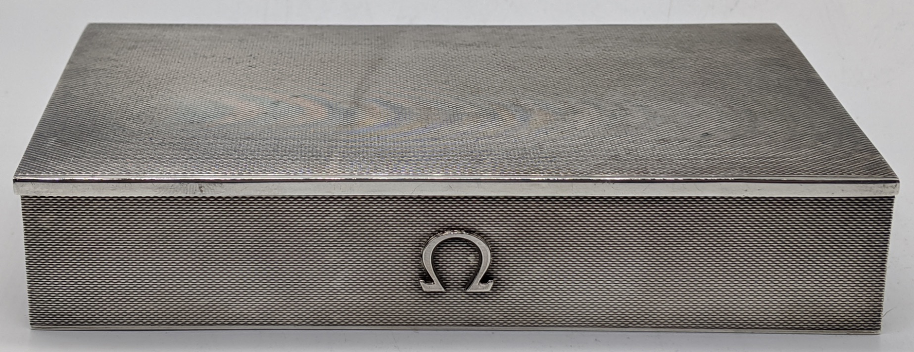 An Omega silver watch box, engine turned finish, hallmarked Birmingham, 1957, maker Atkins Bros