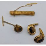 A yellow gold tie clip with a tiger eye mounted pair of cufflinks and stud. Unmarked, tests as gold,