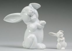 Paar Porzellanfiguren "Lachender Hase"Weiß, glasiert. Groteskendarstellung, eines auf den Hi