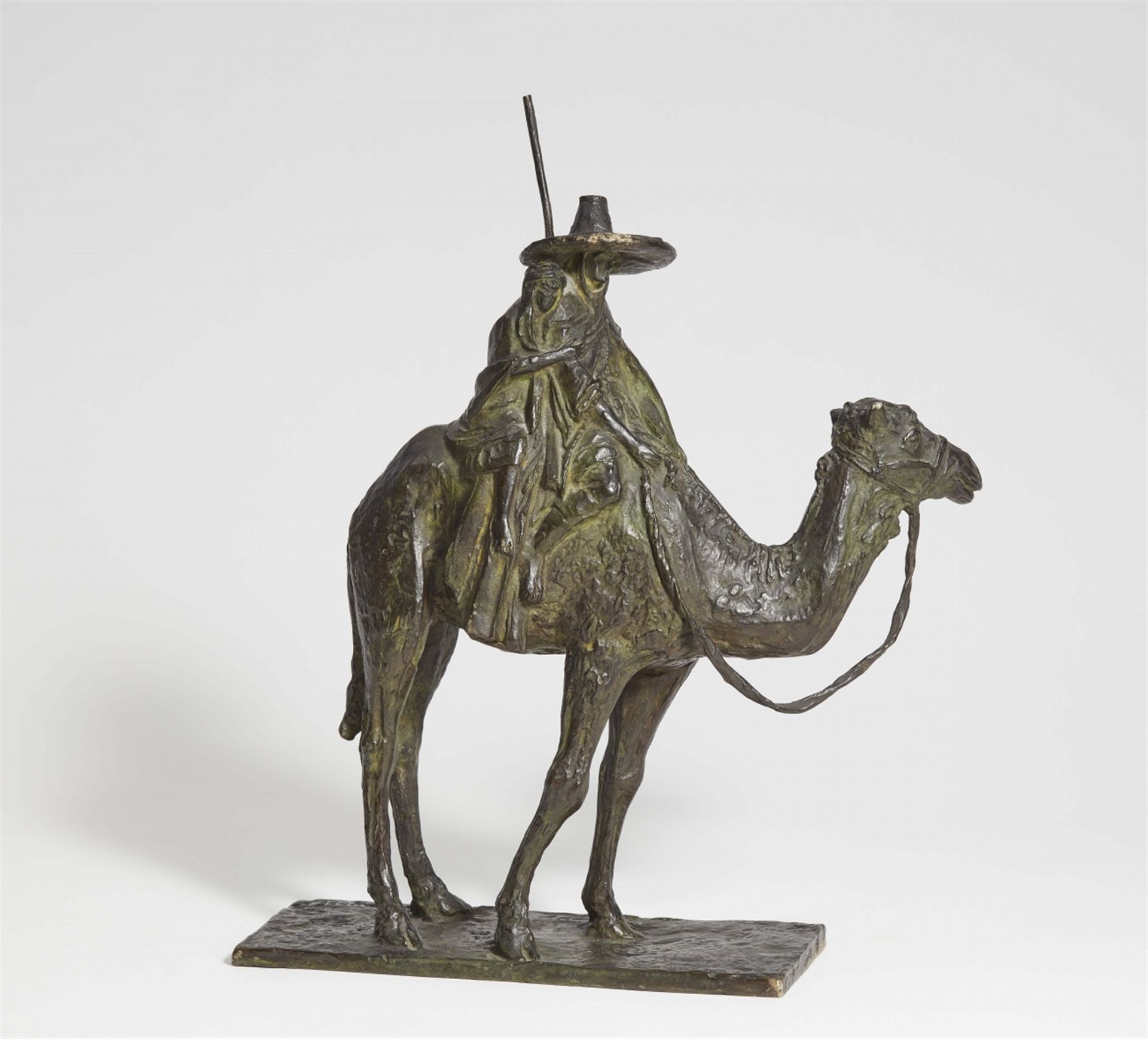 A cast bronze figure of a man riding a camel