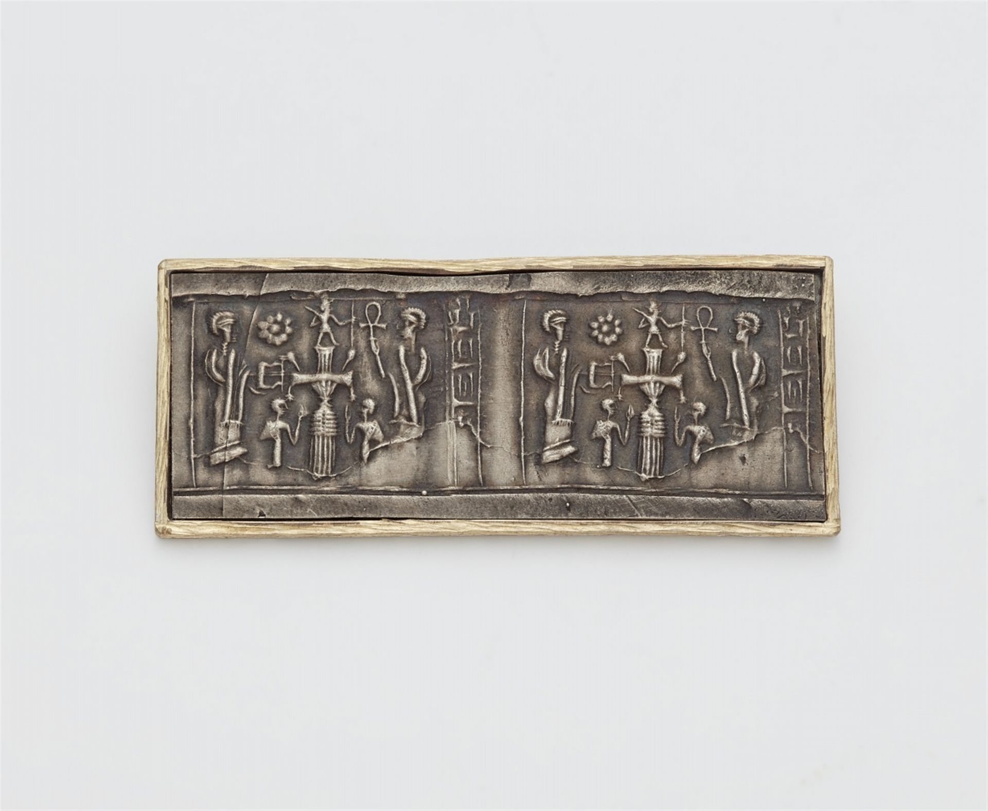 A parcel gilt silver brooch with a cylinder seal impression