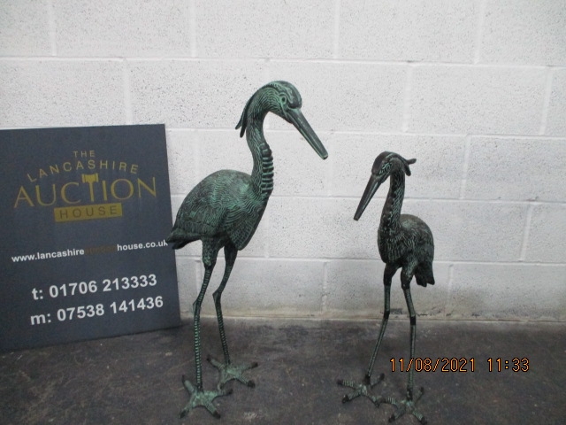 A pair of metal garden storks with bronze effect finish