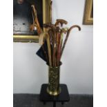 Brass walking stick stand together with a collection of vintage walking sticks