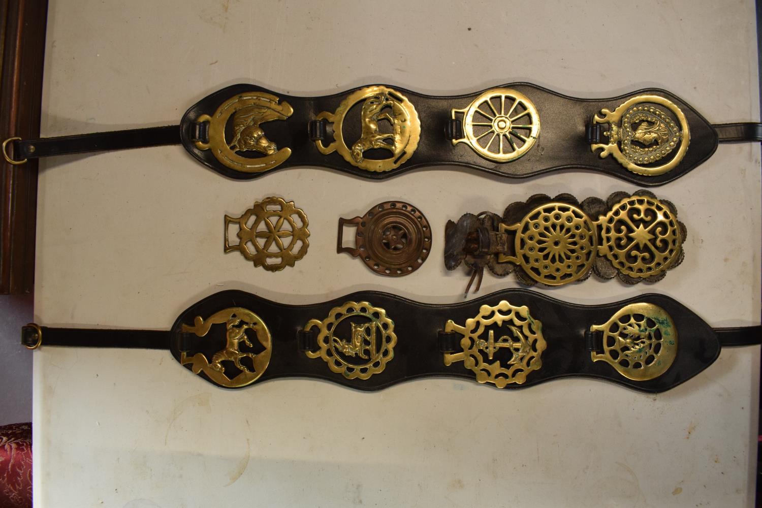 A mixed collection of horse brasses to include a range of modern and old mounted on leathers and