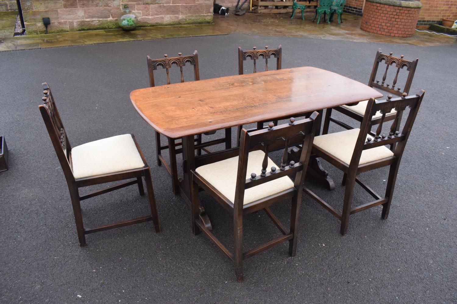 Ercol elm dining table together with 6 matching chairs in a colonial style. Generally in good