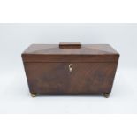 19th century mahogany tea caddy in a sarcophagus form mounted on brass ball feet. In good