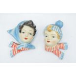 A charming pair of 1950s plaster wall plaques consisting of a boy and a girl dressed in winter