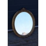 A late 19th/ early 20th century gilt effect wall mirror. 64 cm tall. Oval shape with ornate
