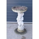 A vintage garden statue in the form of a cherub bird bath on a tree ring base, 85cm tall made from