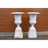 A pair of antique heavy cast iron campagna garden urns on matching cast iron bases. Approximately
