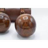 A cased pair of turned 20th century lawn bowls in a leather carry case with monograms.