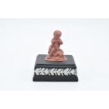 A Wedgwood model of a cherub finial in Terracotta colours mounted on a black jasperware square