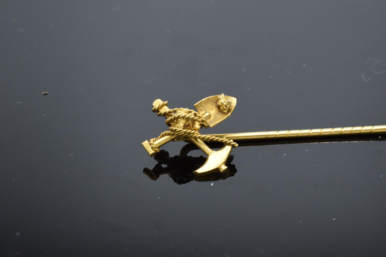 A 9ct gold stick pin in the form of a miner's shovel and pick axe. Tests as 9ct gold. 2.1 grams. 6.5 - Image 2 of 3