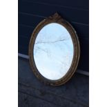 A late 19th/ early 20th century gilt effect wall mirror. 64 cm tall. Oval shape with ornate