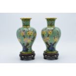 A pair of 20th century cloisonné vases decorated with a green foliage design on wooden bases (2).