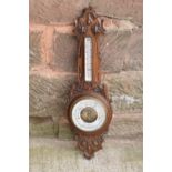 A late Victorian/ Edwardian arts and crafts style carved aneroid barometer by James Lucking and