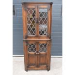 A wooden 20th century Priory style corner display cabinet with glazed upper half. 172cm tall. In