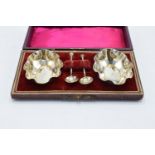 A silver plated cased set of table salts and spoons.