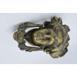 A cast brass door knocker in the form of a figural head. 17cm tall.