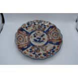 An early 20th century Japanese Imari charger with shaped edge depicting a blue and red floral