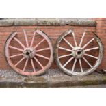 A pair of early 20th century cart wheels with metal rims in a painted pink colour. 130cm diameter.