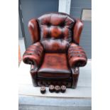 A modern Chesterfield style wingback armchair with button back design raised on 4 wooden feet in