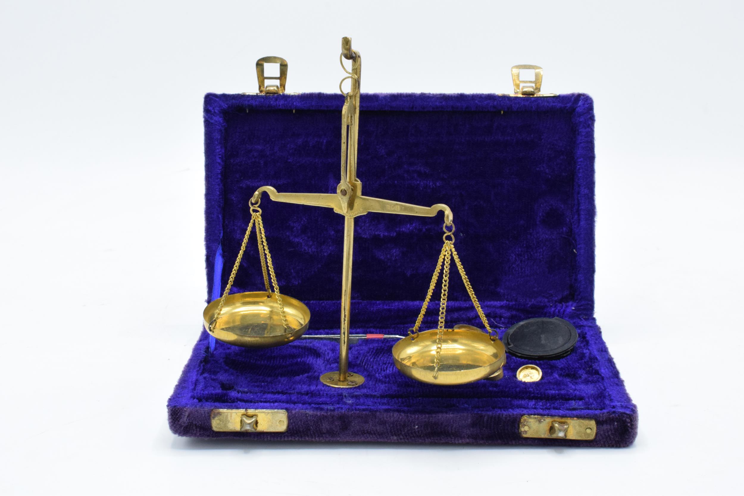 A cased set of brass portable scales with weights as large as 10 grams.
