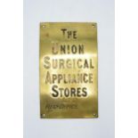 A 20th century cast brass wall mounted sign 'The Union Surgical Appliance Stores Ltd Reg'd