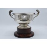 A large silver pedestal bowl raised on a turned wooden plinth with ornate handles. Circa 700