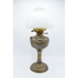 An early 20th century brass oil lamp with column effect body with associated glass shade. 50cm tall.