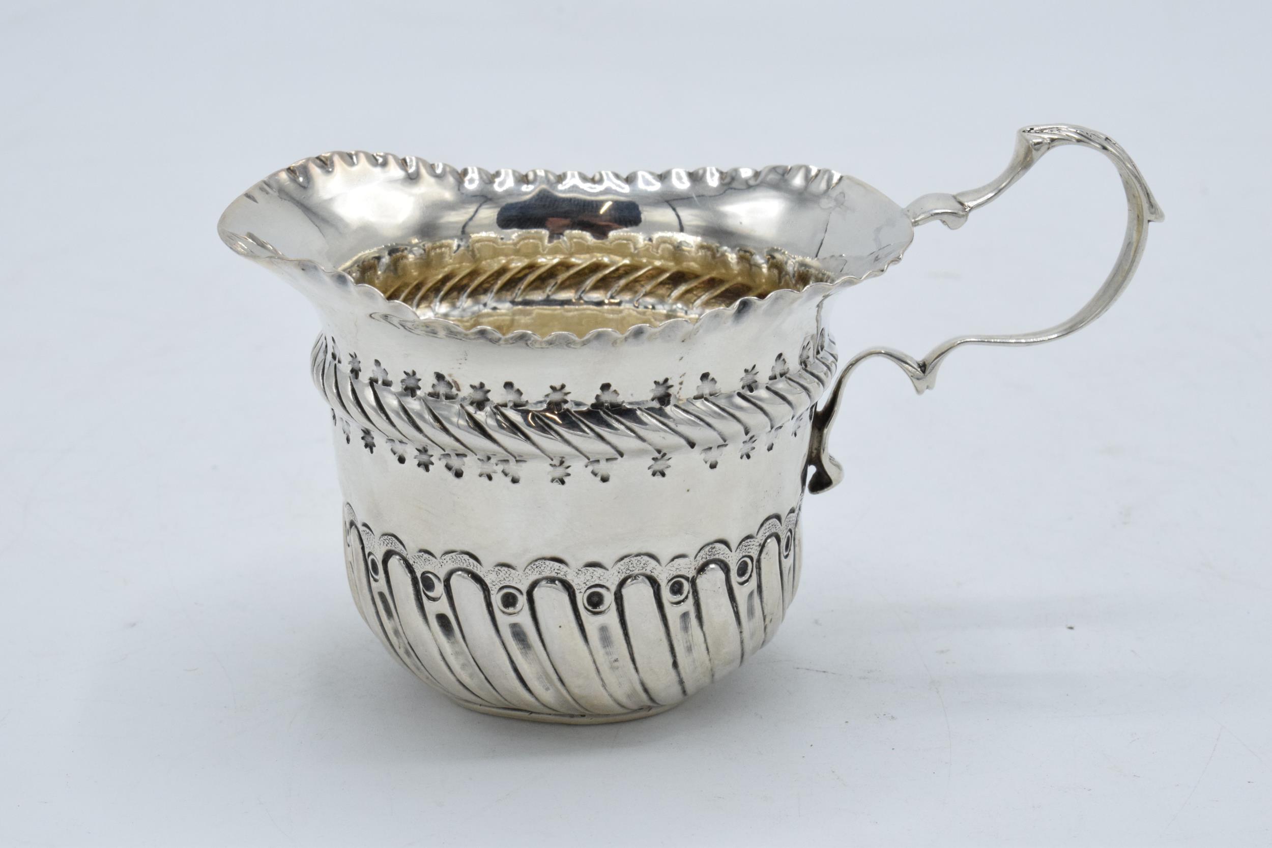 An ornate silver cream jug / sauce jug. London 1890. 53.7 grams. In good condition with some dents