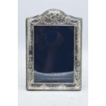 A large hallmarked silver photo frame with embossed decoration. 24.5cm tall. Easel backed. Sheffield