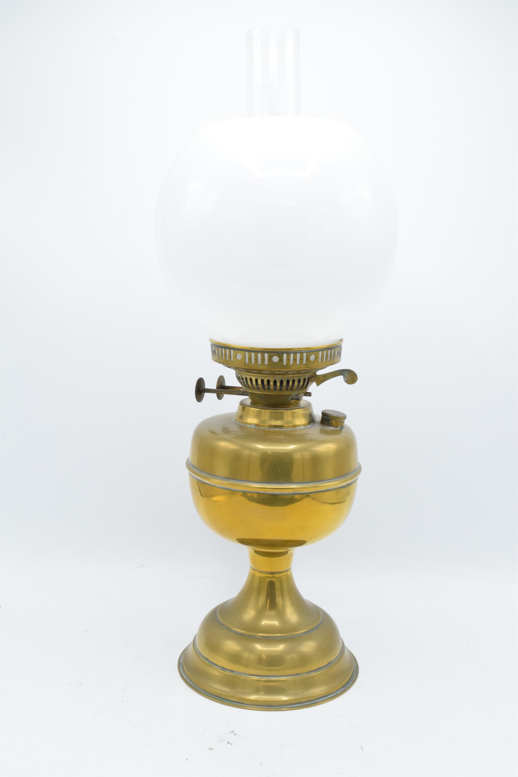 An early 20th century brass oil lamp with associated chimney and shade. 28cm tall without shade.