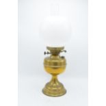 An early 20th century brass oil lamp with associated chimney and shade. 28cm tall without shade.