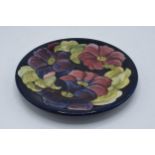 A large Moorcroft 26cm diameter plate in the Hibiscus design on a blue background. In good condition