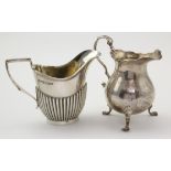 Two silver milk jugs (one raised on three feet), hallmarked Sheffield 1924 & 1930, tallest 10cm